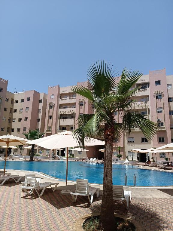 a palm tree in front of a swimming pool at Appartement avec piscine à Mohammedia Plage à 5min in Mohammedia