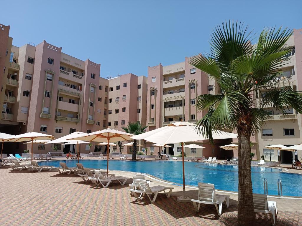 een resort met een zwembad met stoelen en parasols bij Résidence calme avec piscine Plage à 5min in Mohammedia