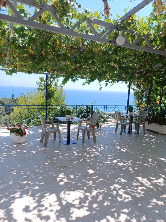 a table and chairs under a pergola overlooking the ocean at Ionian View Guest House in Qeparo