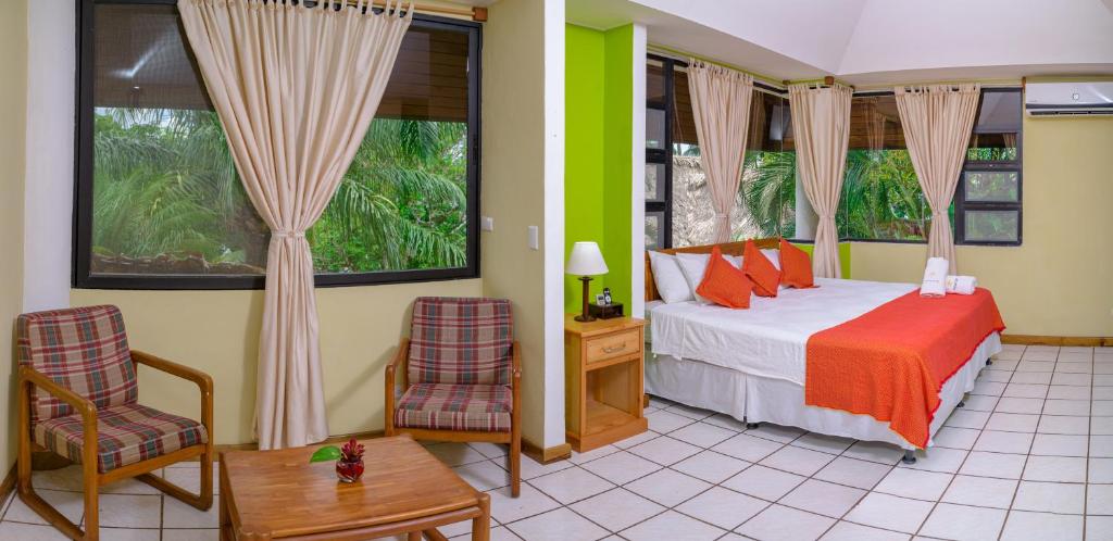 a bedroom with a bed and two chairs and a table at Banana Palms Hotel in Río Dulce
