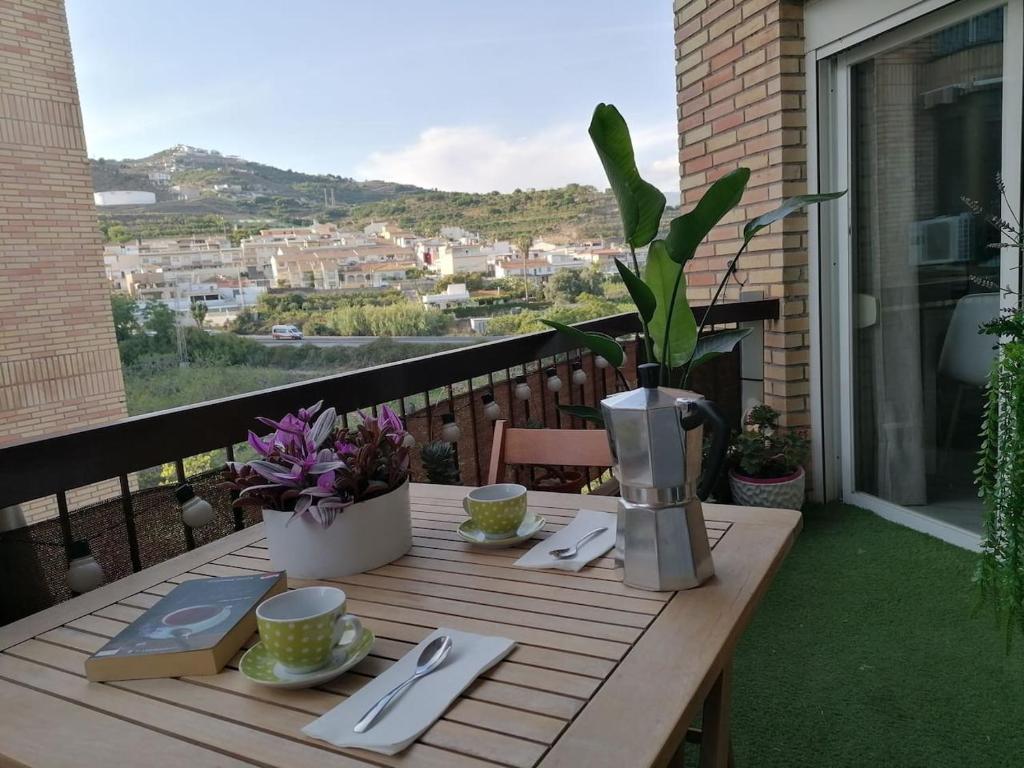 een houten tafel met borden en keukengerei op een balkon bij Apartamento Costa del Sol in Almuñécar