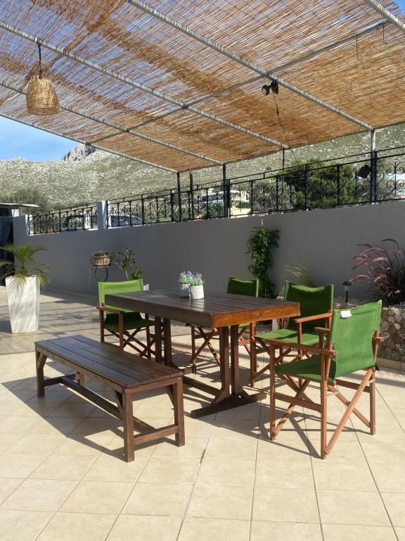 a wooden table and chairs and a table and a bench at Kasteli Cozy House in Archangelos