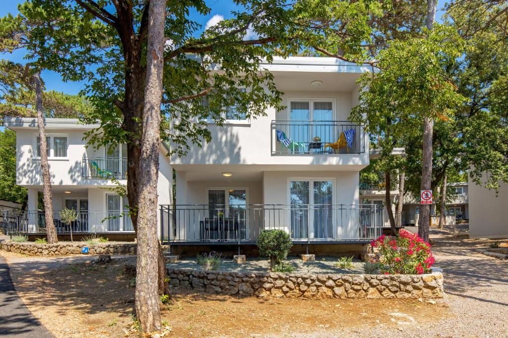 ein weißes Haus mit einem Balkon und Bäumen in der Unterkunft Holiday Homes Oštro in Kraljevica