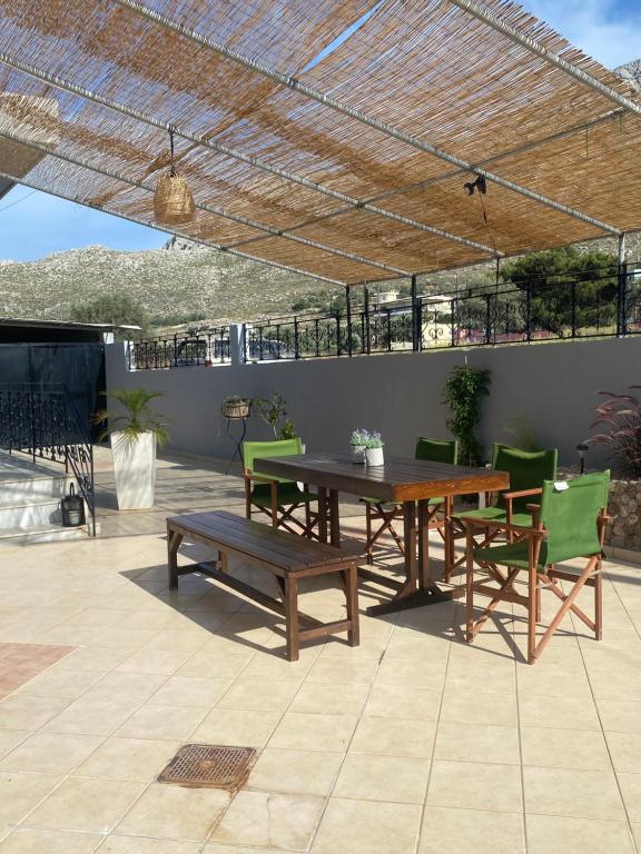a patio with a wooden table and green chairs at Kasteli Cozy House in Archangelos