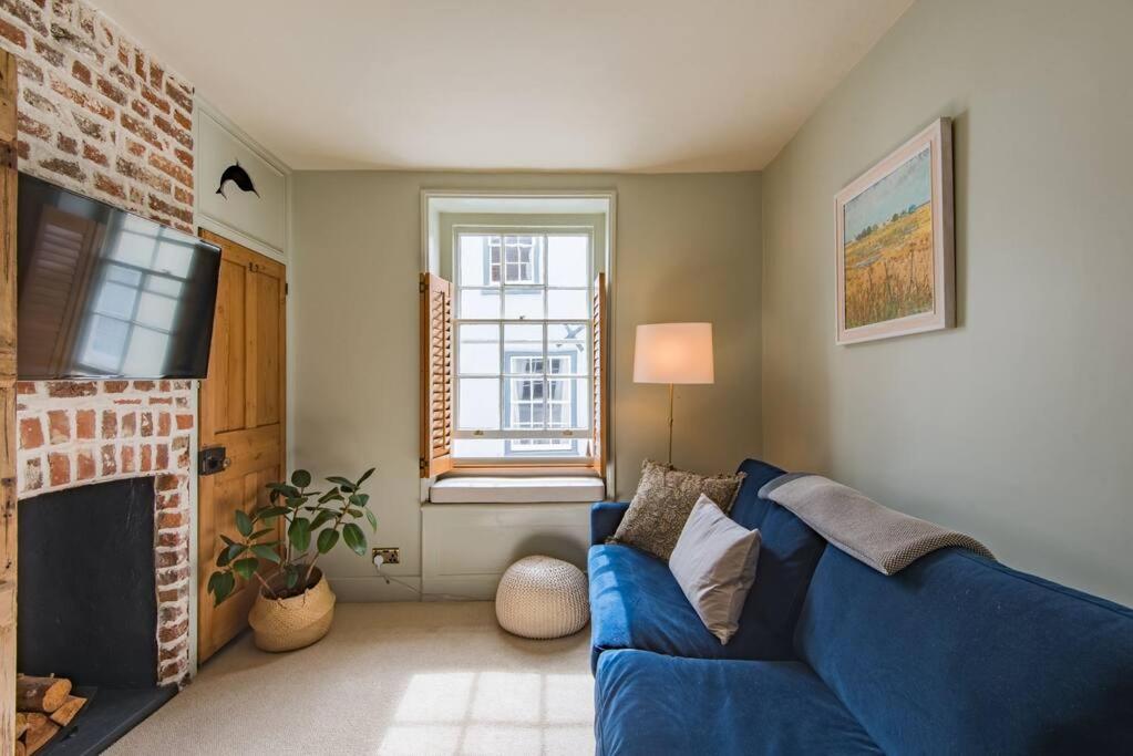 uma sala de estar com um sofá azul e uma lareira em Coop's Landing - Charming seaside bolthole em Deal