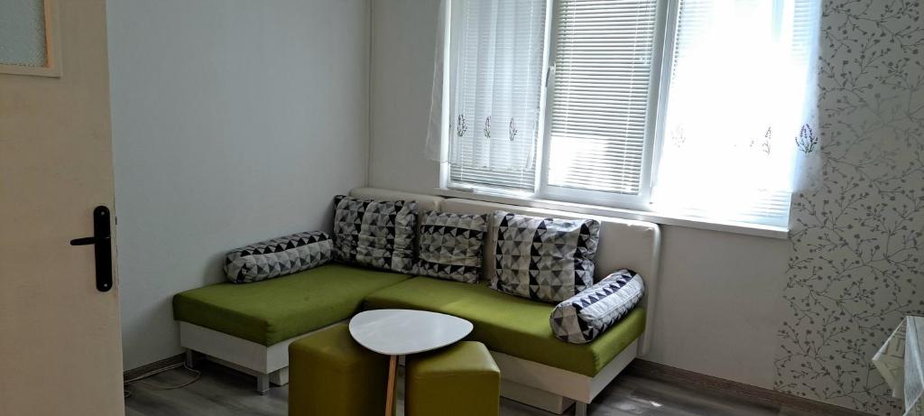 a living room with a green couch and a window at ALANA Apartment in Stara Zagora