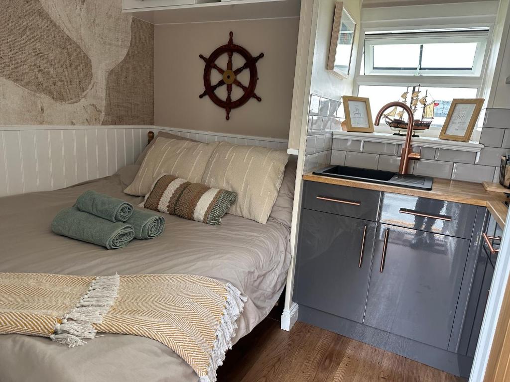 a small bedroom with a bed and a sink at White Mermaid Cottage Anglesey Holidays in Newborough