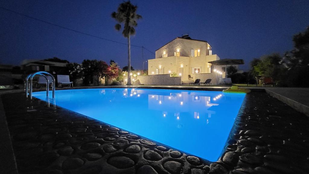 una piscina por la noche con una casa en el fondo en Villa Alex, en Tavronitis