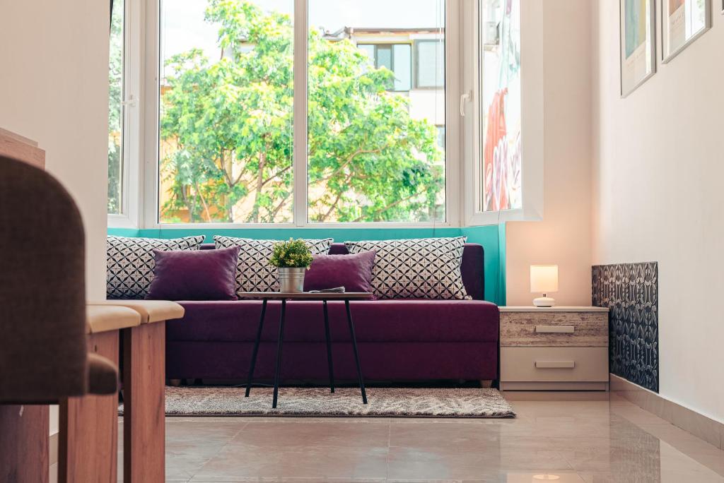 a living room with a purple couch in front of a window at BohoBox Studios in Plovdiv