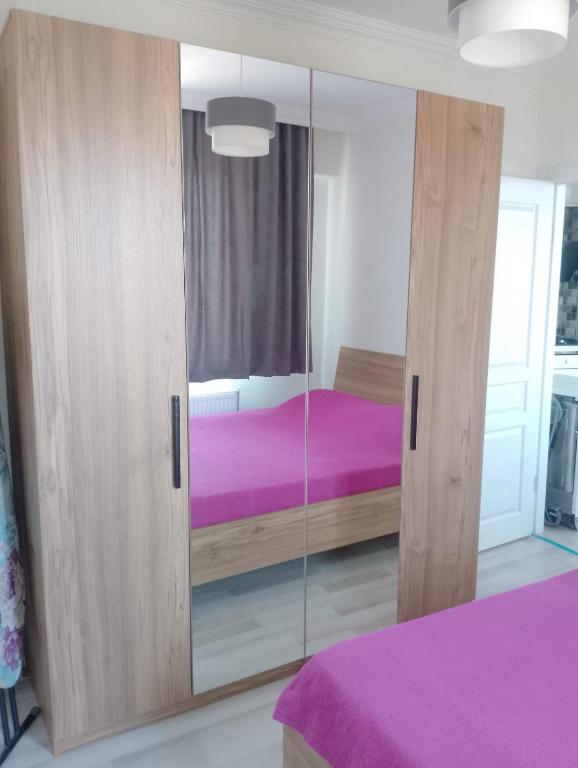 Un dormitorio con un gran armario de madera con una cama morada en Kuzey apart, en Ezine