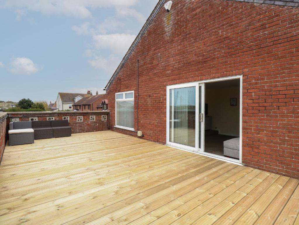 a large deck on the side of a brick building at The Look Out in Sea Palling