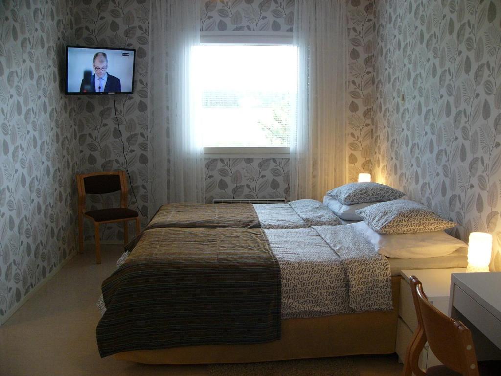 Hotelli Aliisa في Loimaa: غرفة نوم مع سرير وتلفزيون على الحائط