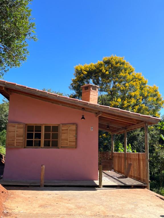 Pousada Recanto dos Pássaros في كونها: منزل وردي صغير مع شجرة