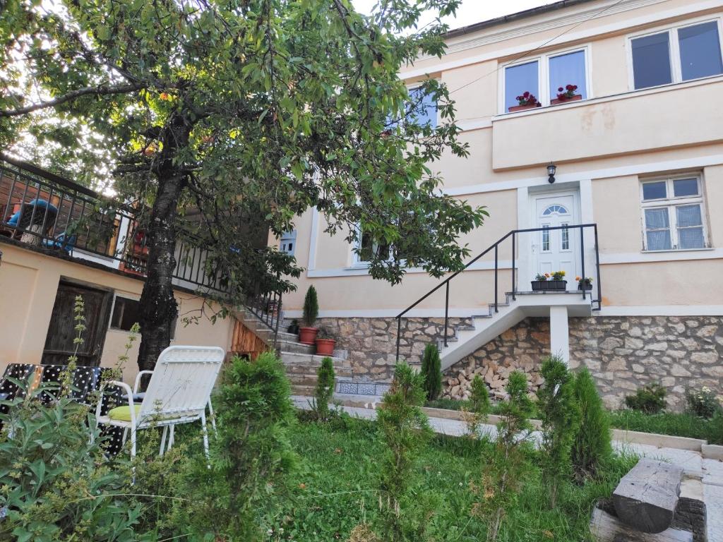 a house with two white chairs in the yard at Guliban in Kruševo