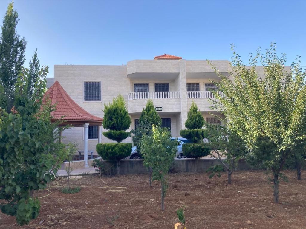 une grande maison avec des arbres devant elle dans l'établissement German-Palestinian Appartement, à Al Khalīl