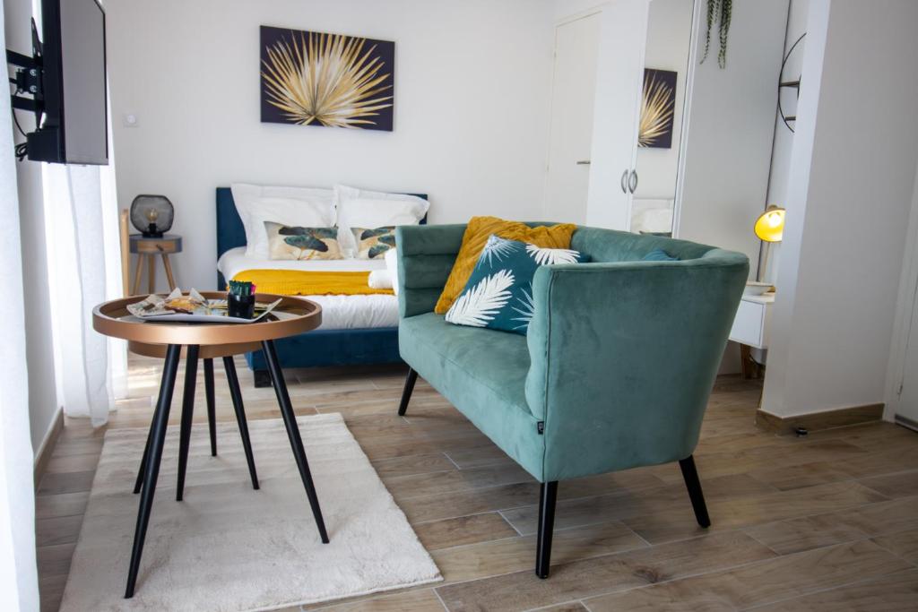 ein Wohnzimmer mit einem grünen Stuhl und einem Bett in der Unterkunft Élégant Studio Climatisé 'Alma 2' - Cœur de Beziers - Wifi Fibre - Netflix in Béziers
