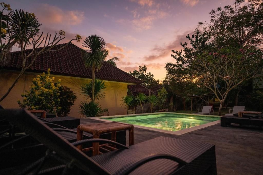una piscina en un patio trasero con puesta de sol en Join Homestay en Kuta Lombok