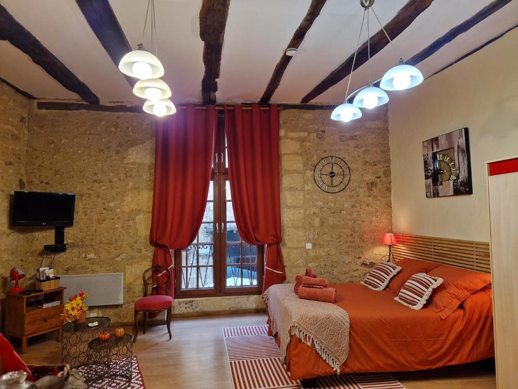 サルラ・ラ・カネダにあるLes Flamboyantsの赤いカーテンとベッド、窓が備わるベッドルーム1室が備わります。