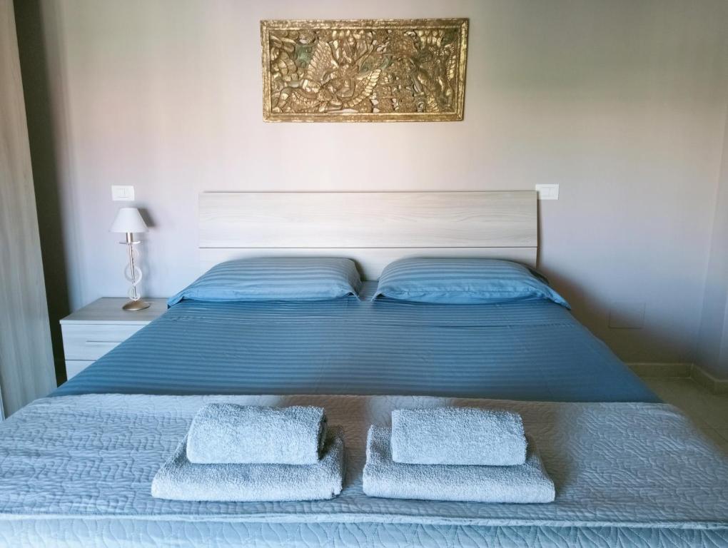 a bed with blue sheets and three towels on it at Appartamento a 50 mt dal mare in Rosignano Solvay