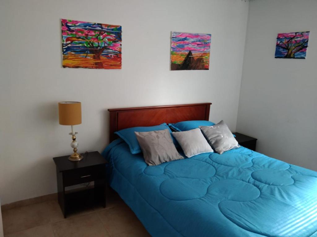 波哥大的住宿－Habitaciones Centro Histórico -est Las aguas，卧室配有蓝色的床,墙上挂有绘画作品