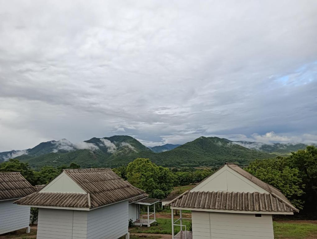 a group of houses with mountains in the background at Pai sunrise camping resort in Pai