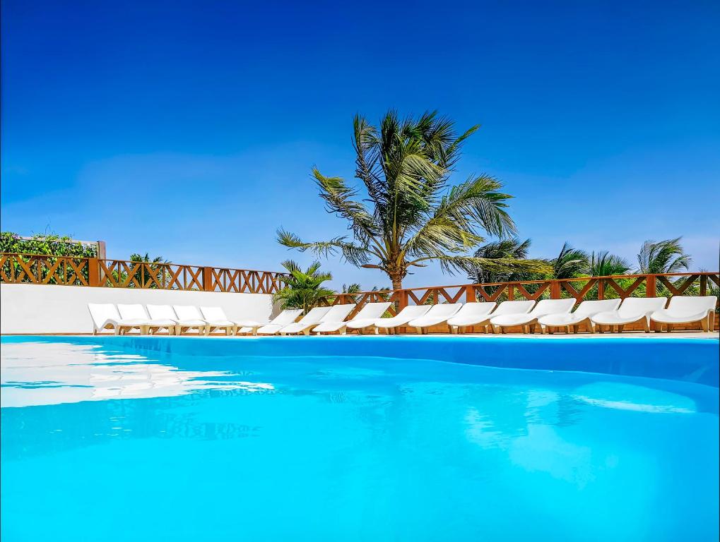 uma piscina com espreguiçadeiras e uma palmeira em Mini Hotel em Jericoacoara