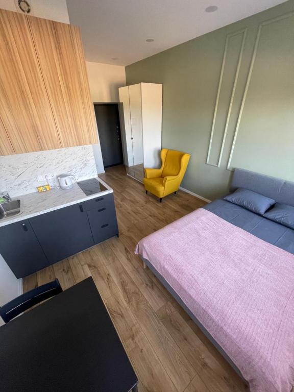 ein Schlafzimmer mit einem Bett und einem gelben Stuhl in der Unterkunft Airport Apartment 22 Self Check-In in Vilnius