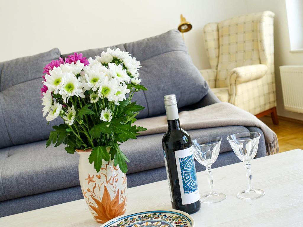 a bottle of wine and a vase with flowers on a table at Penthaus Kranichholz in Lüdinghausen