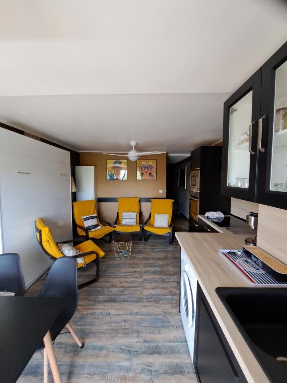 salon z żółtymi krzesłami i kuchnią w obiekcie Appartement avec parking Cap d'Agde, La Falaise w Cap d'Agde