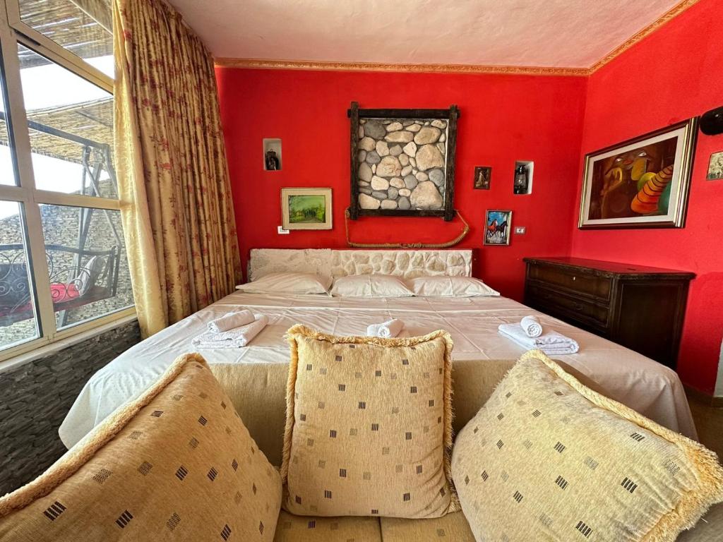 a bedroom with red walls and a bed with two pillows at Hotel Vila "Oda E Miqve" in Vlorë