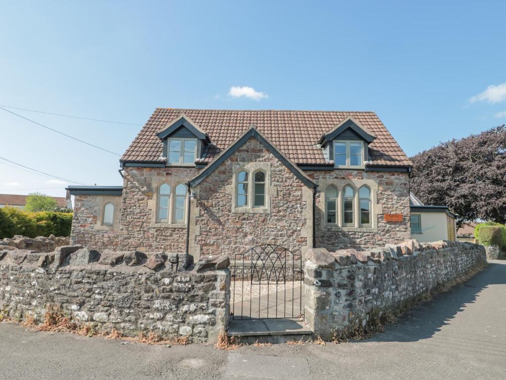 a brick house with a stone wall and a gate at The Old Schoolrooms in Radstock