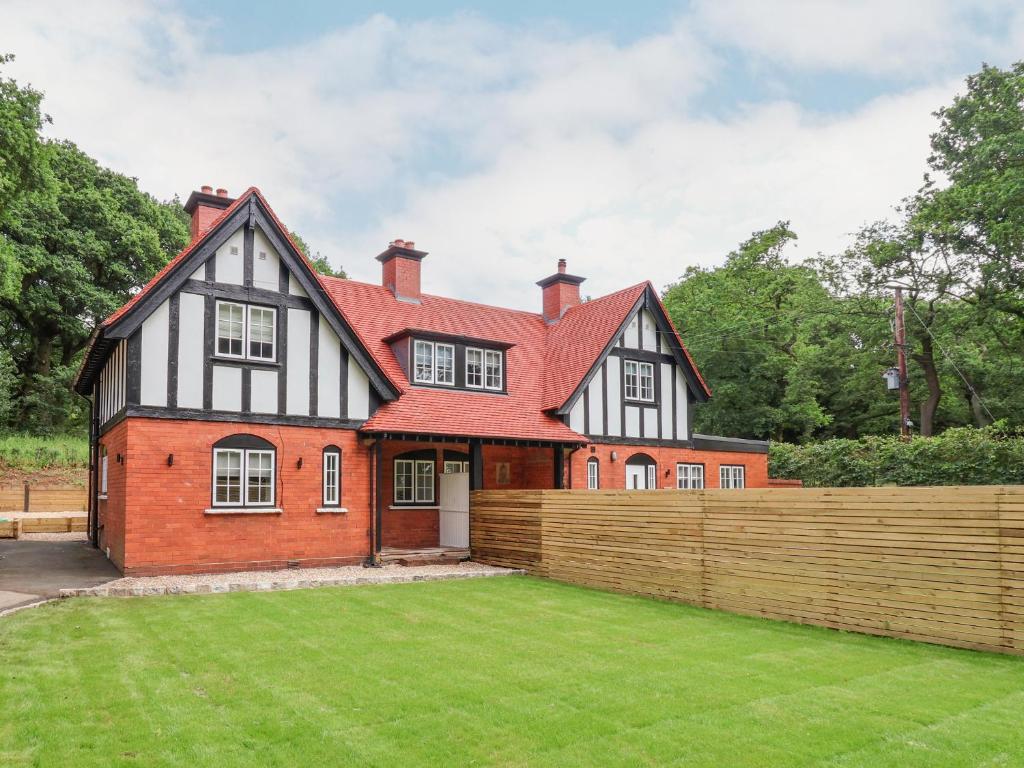 a house with a fence in front of a yard at 1 Golf Links Cottages in Northwich