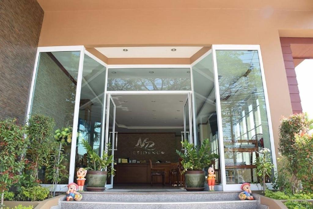 een glazen ingang naar een gebouw met potplanten bij NP Residence in Nakhon Phanom