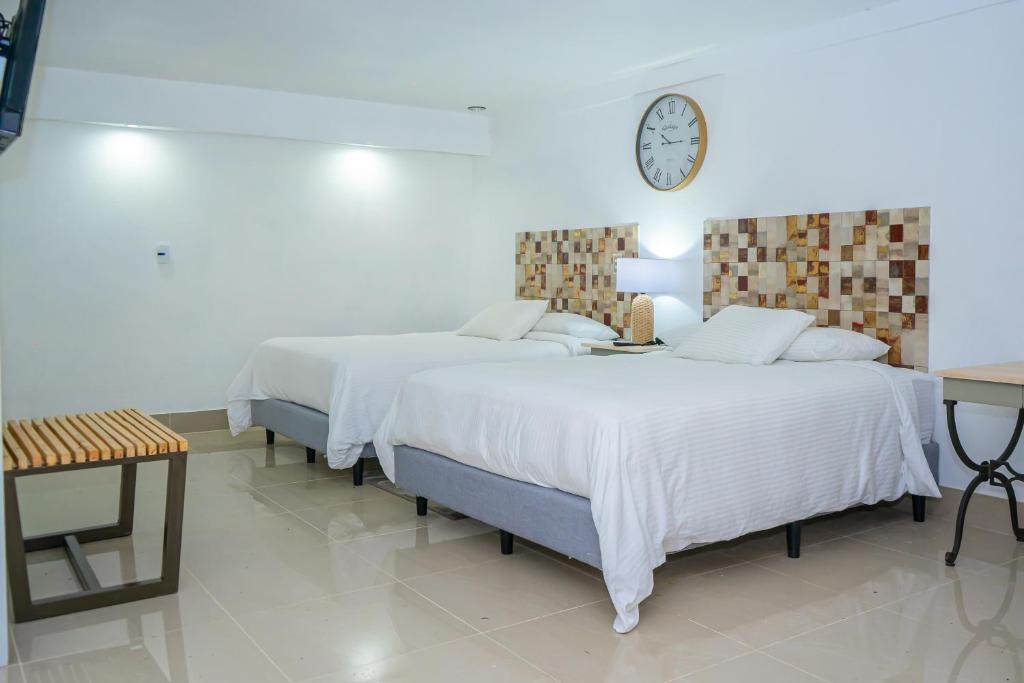 2 camas en una habitación con un reloj en la pared en Hotel Zima, en San Isidro
