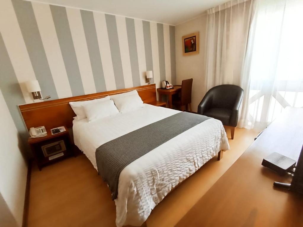 a hotel room with a bed and a chair at Hotel Runcu Miraflores in Lima