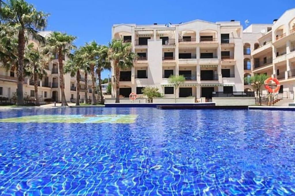 a large swimming pool in front of a building at Ático con acceso directo al mar in Miami Platja