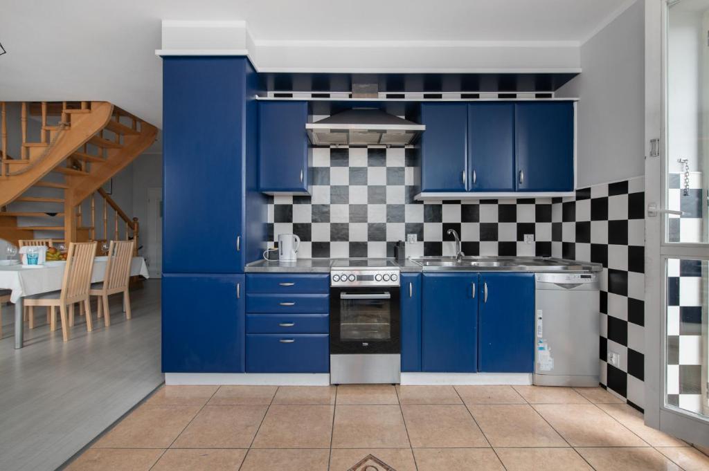 a kitchen with blue cabinets and a checkered wall at Tjiraso Apartment in Gdańsk