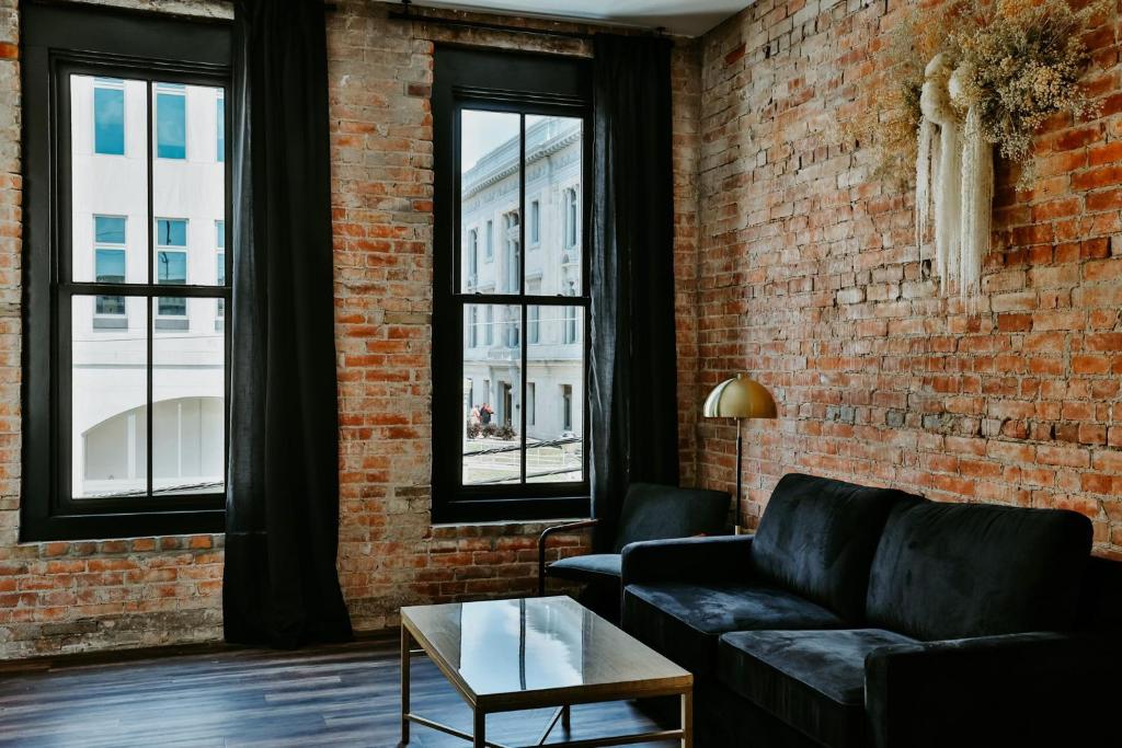 a living room with a couch and a brick wall at Urban Collective Boutique Hotel in Edwardsville