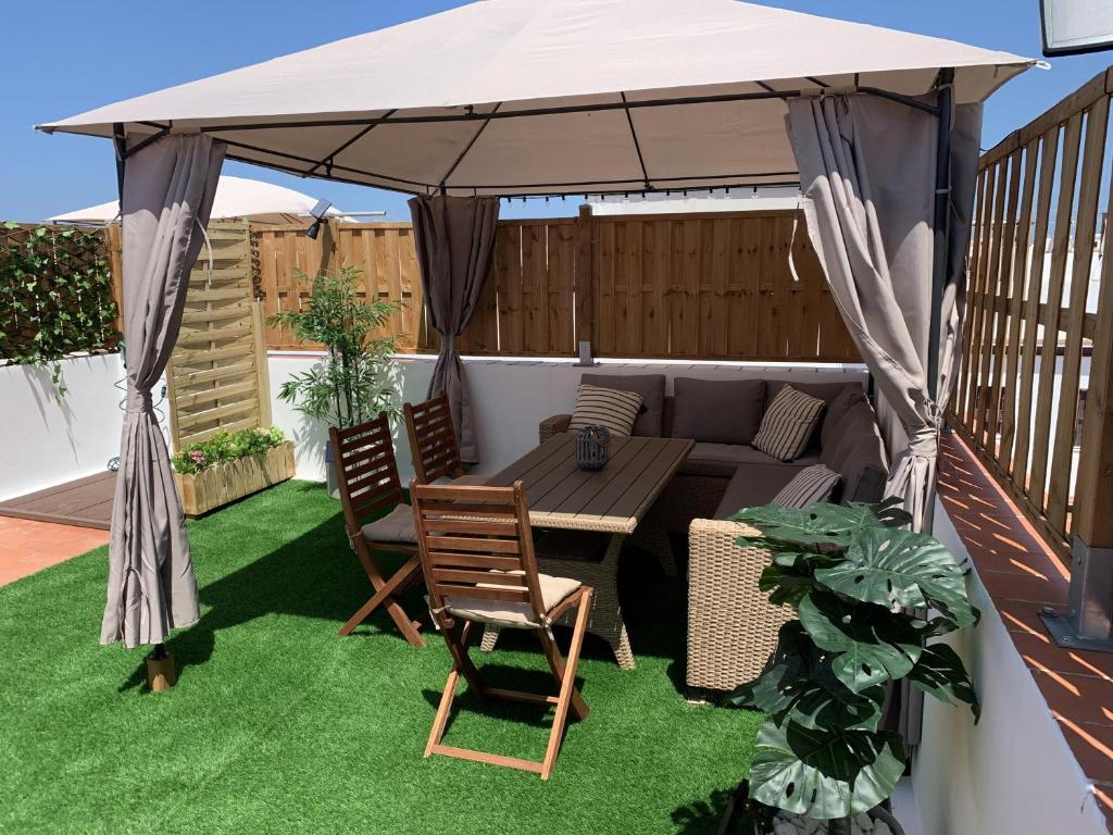 a patio with a table and chairs under a canopy at Apartamento Sotavento Chipiona in Chipiona