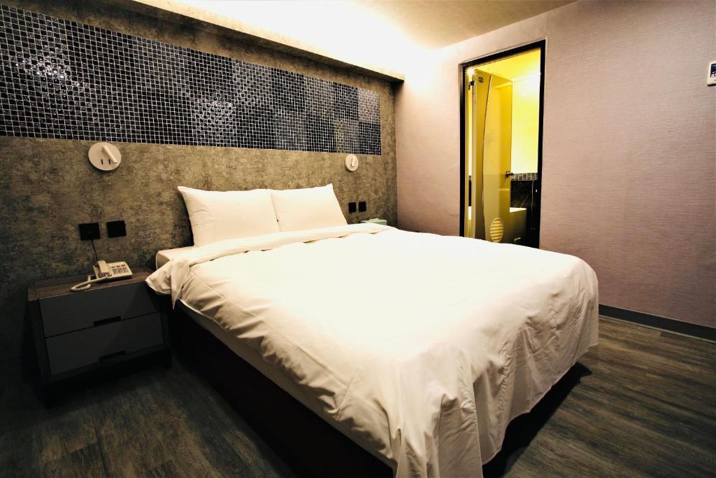 a bedroom with a large white bed and a yellow door at Golden Home Hotel in Taipei