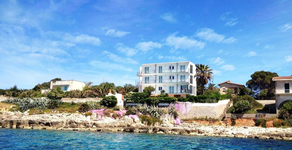 a white building on a hill next to the water at Villa Grachira in Fertilia