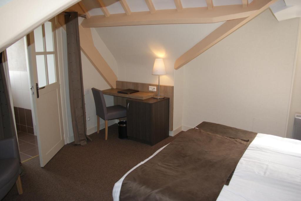 a bedroom with a bed and a desk with a lamp at La Vieille Auberge in Le Mont Saint Michel