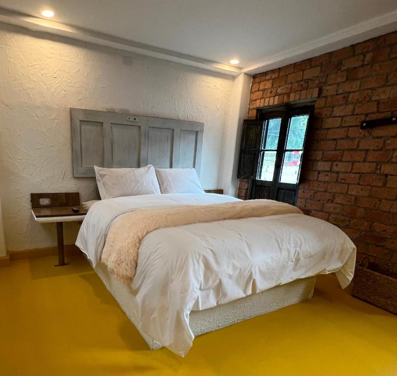 a bedroom with a large bed and a brick wall at OPE Suites Usaquen in Bogotá