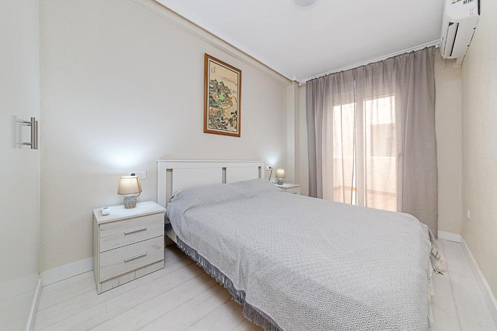 a white bedroom with a bed and a window at Apartamento Fragata in Torrevieja