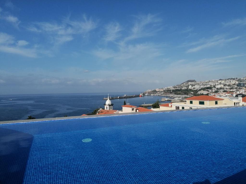 a large blue swimming pool with a view of the ocean at Apartments Madeira Barreirinha in Funchal