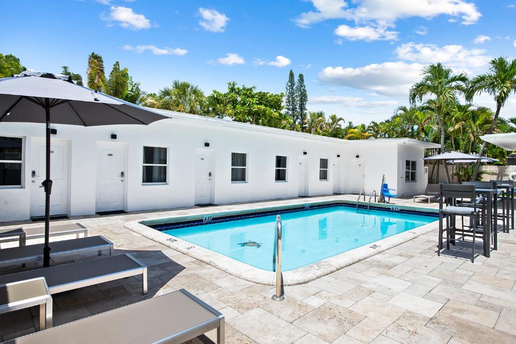 a swimming pool with chairs and an umbrella next to a building at The Hotel Deauville in Fort Lauderdale