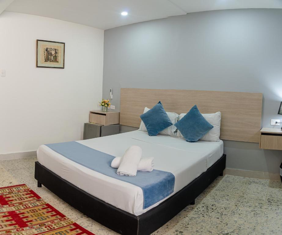 a bedroom with a large bed with blue and white pillows at Casa Franco Hotel in Cartagena de Indias