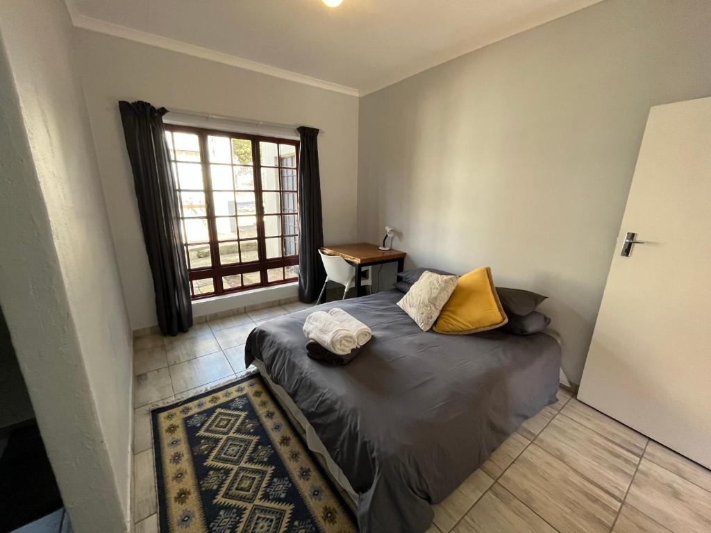 Schlafzimmer mit einem Bett, einem Fenster und einem Tisch in der Unterkunft Casa Bravo - Cozy Traveller in Pretoria