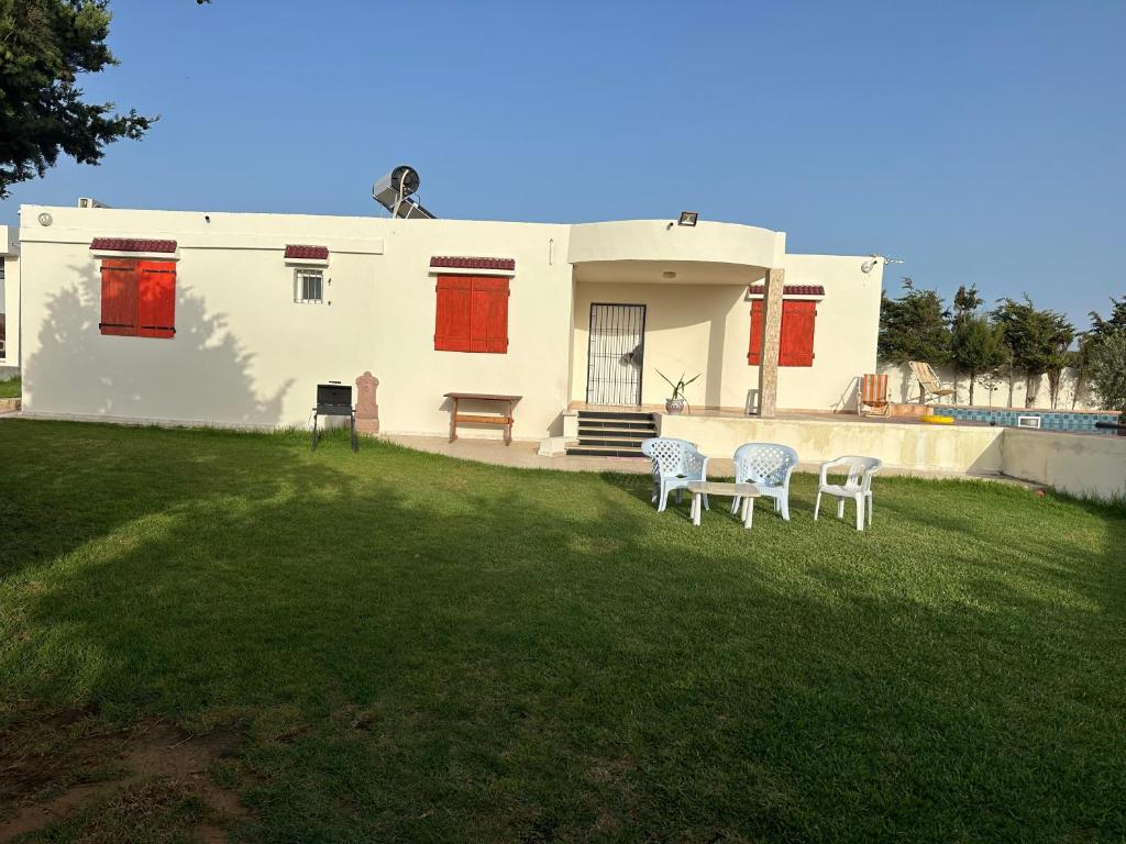 a house with two chairs and a table in the yard at DAR AZAIEZ El Haouaria Villa 4 Chambres climatisé belle piscine in El Haouaria