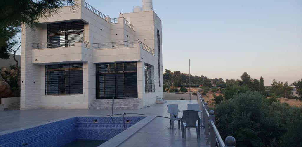 a house with chairs on the balcony of it at The Pine Tree Chalet in Jerash